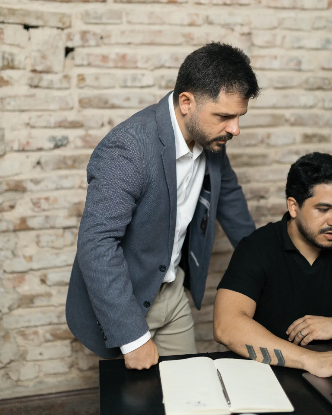 Tiago Asfora de pé ao lado de um analista, acompanhando o trabalho na mesa